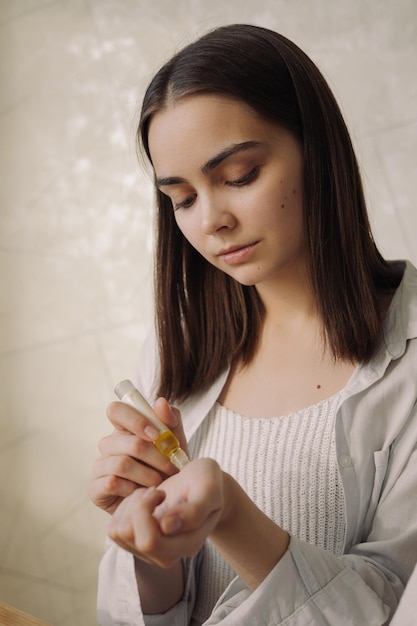 Jeune femme appliquant de l'huile essentielle dans un rouleau et profitant de l'aromathérapie à la maison