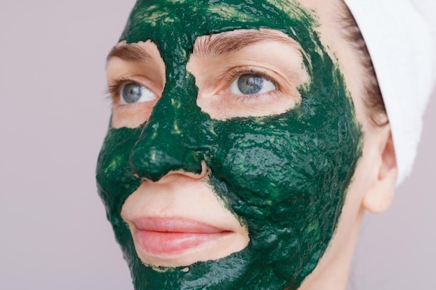 Photo une jeune femme applique un masque vert sur son visage avec une brosse soins de la peau du visage à la maison