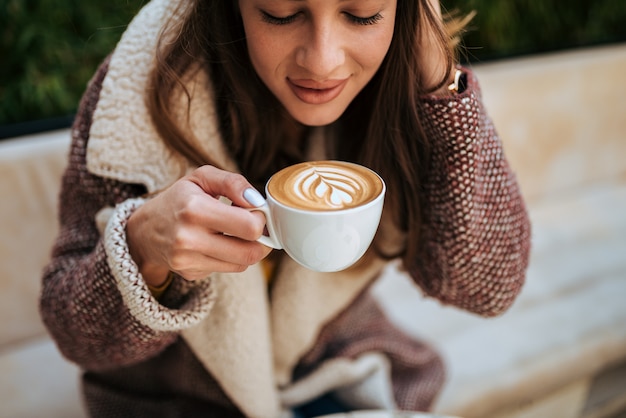 Jeune femme en appréciant le café d&#39;art latte.