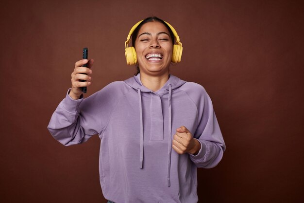 Jeune femme appréciant joyeusement la musique sur mobile avec des écouteurs