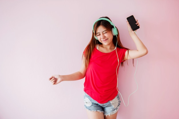 Jeune femme appréciant avec de la musique de téléphone intelligent dans la maison