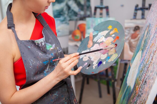 Jeune femme appréciant la peinture dans son studio d'art