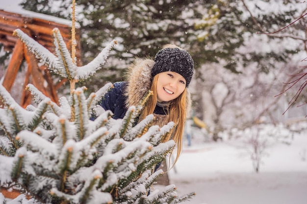 La jeune femme apprécie un jour neigeux d'hiver dans une forêt neigeuse