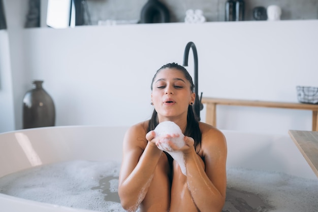 La jeune femme apprécie la mousse tout en prenant un bain