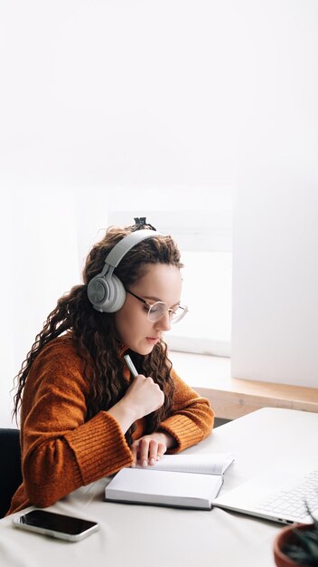 Jeune femme apprenant à distance à domicile assistant à des réunions de classe virtuelle et de conférence à distance sur ordinateur portable