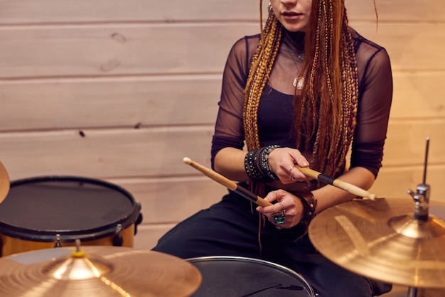 Photo jeune femme apprenant à jouer de la batterie pendant la leçon de musique en studio