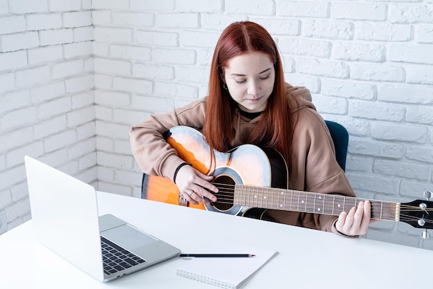 Jeune femme apprenant à jouer de la guitare à la maison