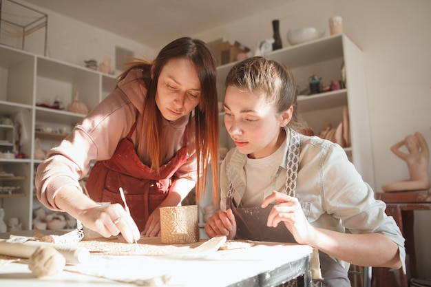 Jeune femme apprenant la poterie d'une céramiste