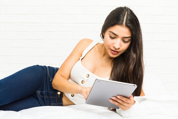 Jeune femme arabe au lit avec une tablette