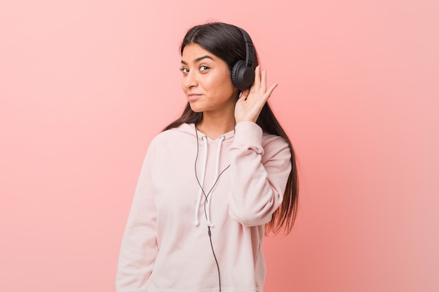 Jeune femme arabe écoutant de la musique en essayant d'écouter un commérage.