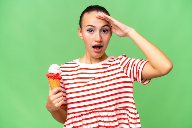 Jeune femme arabe avec une glace au cornet sur fond isolé avec une expression de surprise