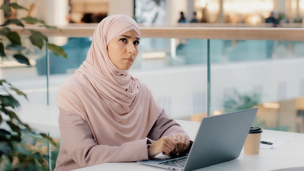 Une jeune femme arabe inquiète et pensive réfléchie travaillant sur un ordinateur portable pense à une nouvelle idée de démarrage