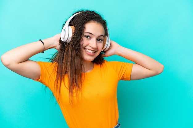 Jeune femme arabe isolée sur fond bleu écoutant de la musique