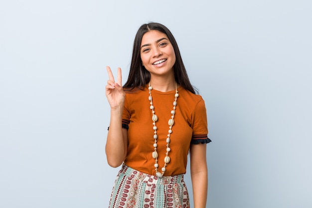 Jeune femme arabe joyeuse et insouciante montrant un symbole de paix avec les doigts.