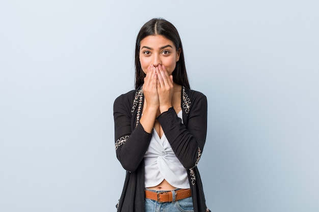 Jeune femme arabe naturelle et jolie rire de quelque chose, couvrant la bouche avec les mains.