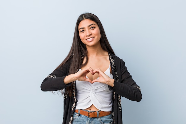 Jeune femme arabe naturelle et jolie souriant et montrant une forme de coeur avec les mains.