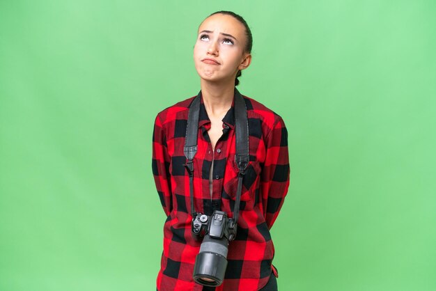 Jeune femme arabe photographe sur fond isolé et levant les yeux