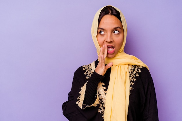Une jeune femme arabe portant un costume arabe typique isolé sur fond violet dit une nouvelle secrète de freinage à chaud et regarde de côté