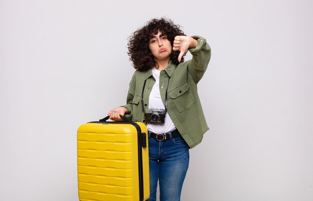 Jeune femme arabe se sentant cross, en colère, ennuyé, déçu ou mécontent, montrant les pouces vers le bas avec un concept de voyage look sérieux