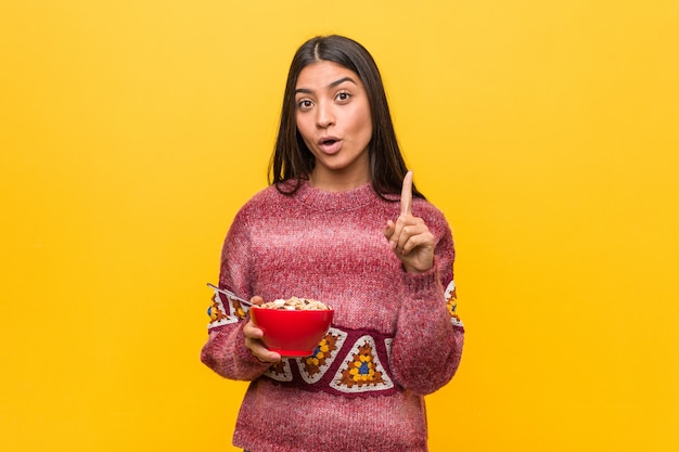 Jeune femme arabe tenant un bol de céréales ayant une très bonne idée, concept de créativité.