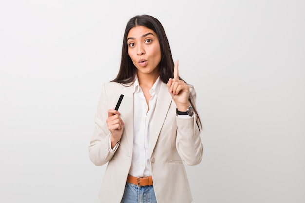 Jeune femme arabe tenant une carte de crédit ayant une excellente idée, concept de créativité.