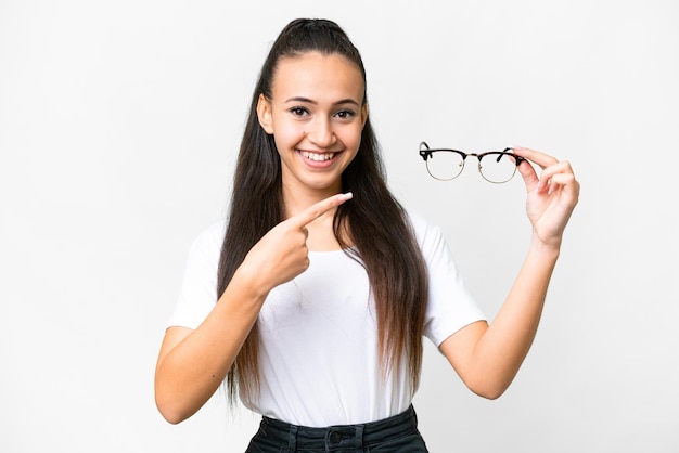 Jeune femme arabe tenant des lunettes sur fond blanc isolé et le pointant