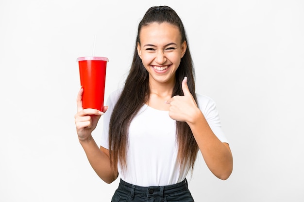 Jeune femme arabe tenant un soda sur fond blanc isolé avec une expression faciale surprise