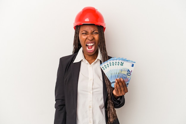 Jeune femme architecte afro-américaine tenant des factures isolées sur fond blanc criant très en colère et agressive.