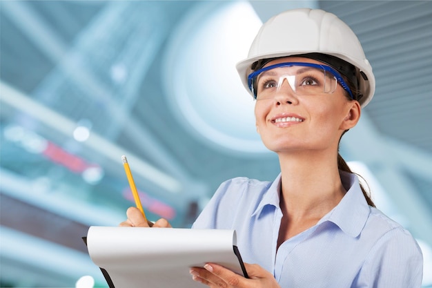 Jeune femme architecte en casque avec presse-papiers