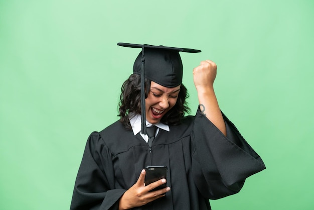 Jeune femme argentine diplômée de l'université sur fond isolé avec téléphone en position de victoire