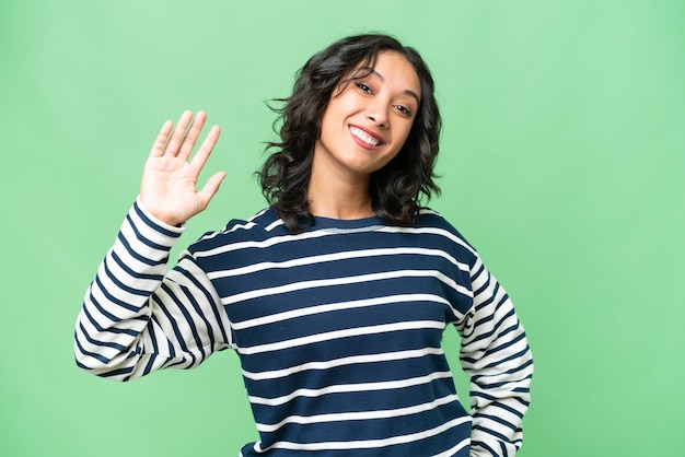 Photo jeune femme argentine sur fond isolé saluant avec la main avec une expression heureuse