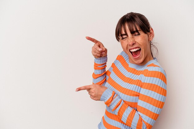 Jeune femme argentine isolée sur fond blanc excité pointant avec les index loin.