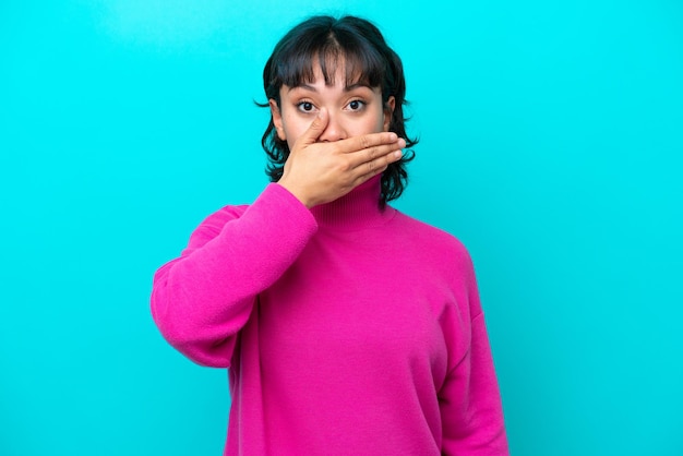 Jeune femme argentine isolée sur fond bleu couvrant la bouche avec la main