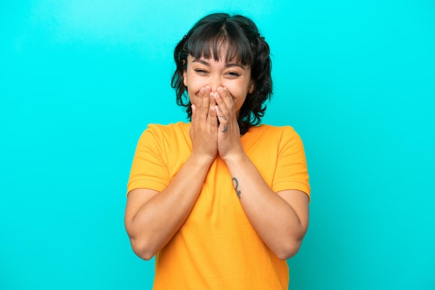 Jeune femme argentine isolée sur fond bleu heureuse et souriante couvrant la bouche avec les mains