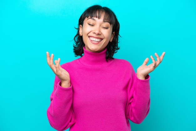 Jeune femme argentine isolée sur fond bleu souriant beaucoup