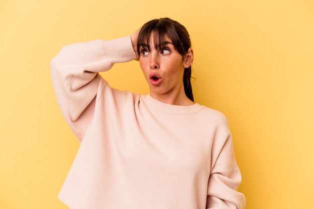 Jeune femme argentine isolée sur fond jaune étant choquée, elle s'est souvenue d'une réunion importante.