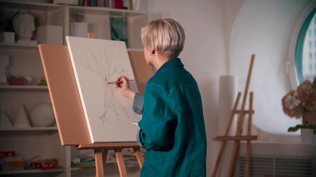 Une jeune femme artiste coloriant sa peinture de l'arbre