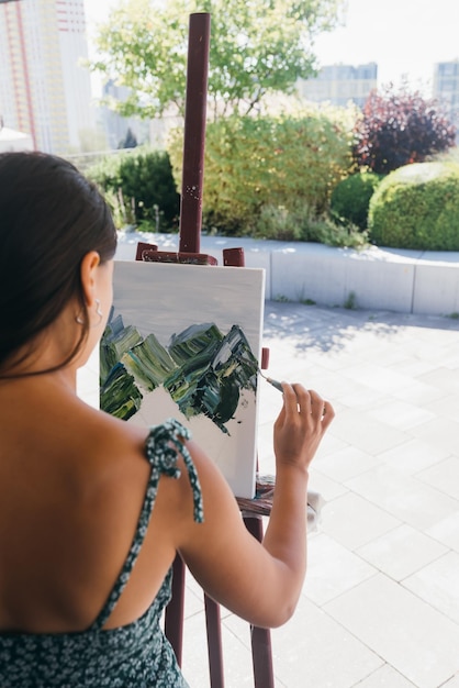 Jeune femme artiste peint avec une spatule sur la toile