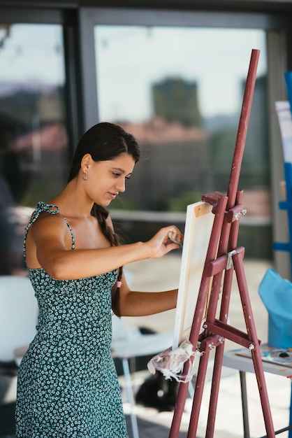 Jeune femme artiste peint avec une spatule sur la toile