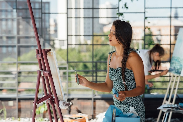 Jeune femme artiste peint avec une spatule sur la toile