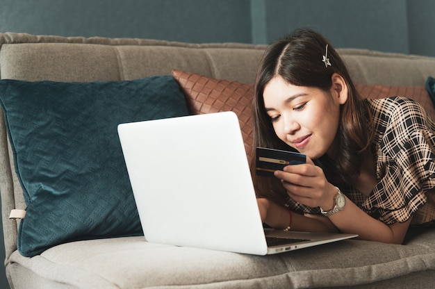 Jeune femme asiatique à l'aide d'une carte de crédit pour les achats en ligne