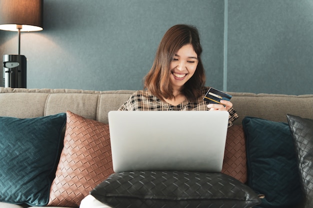 Photo jeune femme asiatique à l'aide d'une carte de crédit pour les achats en ligne