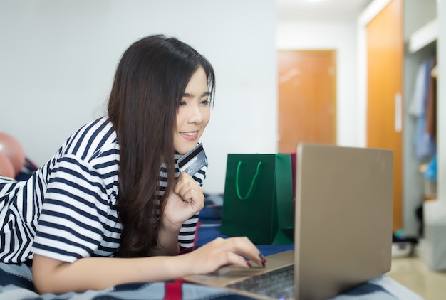 Jeune femme asiatique à l&#39;aide d&#39;un ordinateur portable et détenant une carte de crédit.