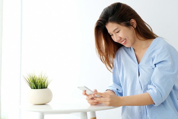 Jeune Femme Asiatique à L'aide De Téléphone Intelligent Avec Sourire