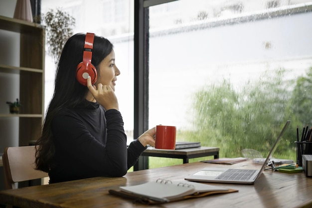 Une jeune femme asiatique aime boire du café et écouter de la musique avec un casque