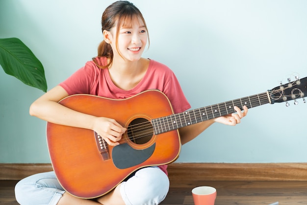 Jeune femme asiatique, apprentissage de la guitare à la maison