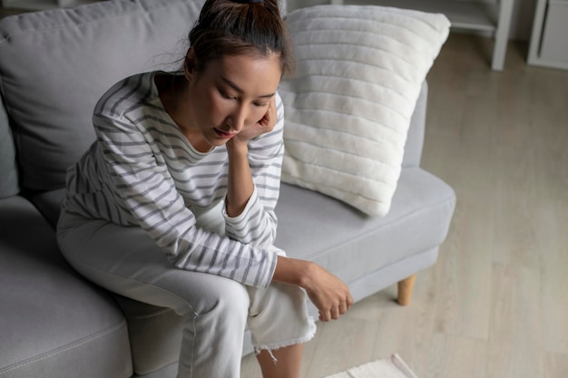 Photo jeune femme asiatique assise sur le canapé à la maison se sentant triste fatiguée et inquiète souffrant de dépression en santé mentalefemme souffrant de problèmes de santé mentale