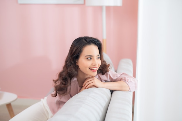 Jeune femme asiatique assise sur le canapé et se détendre.