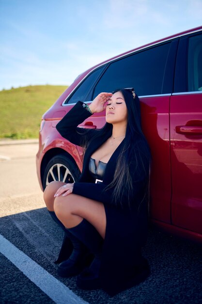 Photo une jeune femme asiatique assise sur la route près de sa voiture et détournant le regard