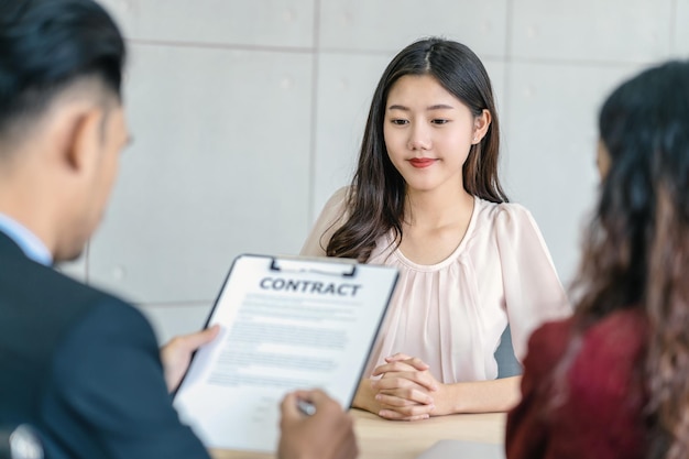 Jeune femme asiatique attendant de signer le contrat avec deux directeurs avec un mouvement positif